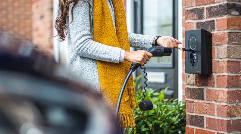 Latausasema omakotitalon seinällä, latausjohto kytketään autoon